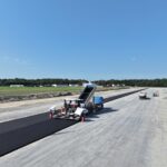29.08.2024 Die Asphalt-Tragschicht wird auf die zukünftige Start- und Landebahn aufgetragen